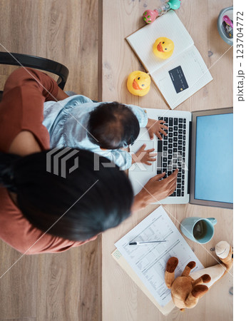 top view, baby and mother working on a laptop at table at home while taking care of her child. Kid, technology and woman with remote job typing on a computer with documents for a project at her house top view, baby and mother working on a laptop at table at home while taking care of her child. Kid, technology and woman with remote job typing on a computer with documents for a project at her house 123704772