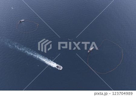 A bird's eye view of a large fishing vessel retrieving its nets. Impressive view with birds flying around fishing boat fishing in blue waters. A bird's eye view of a large fishing vessel retrieving its nets. Impressive view with birds flying around fishing boat fishing in blue waters. 123704989