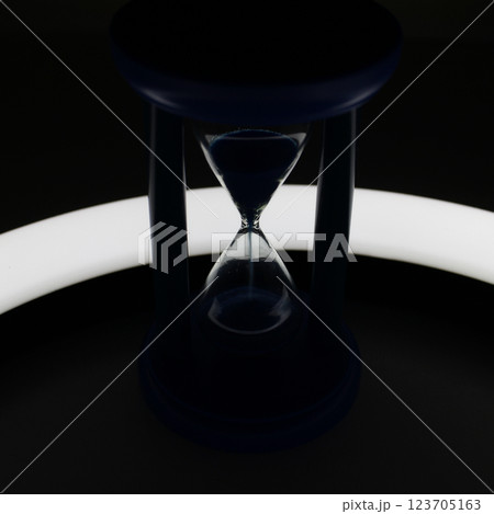 Illuminated Trickle Of Sand Inside Hourglass In Darkness Closeup View  123705163