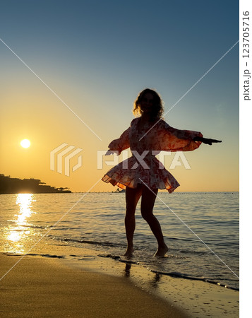 Silhouette of young woman dancing at the sandy beach 123705716
