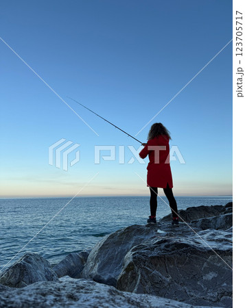 Young happy woman is fishing at sea during spring vacation Young happy woman is fishing at sea during spring vacation 123705717