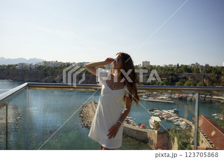 Smiling woman in white dress enjoying city harbor view Smiling woman in white dress enjoying city harbor view 123705868