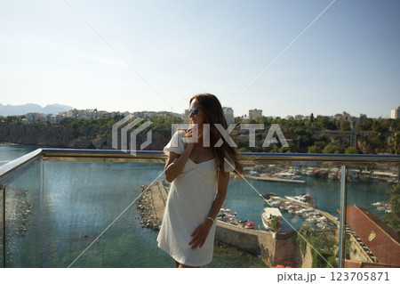 Happy woman in white dress enjoying harbor view from balcony Happy woman in white dress enjoying harbor view from balcony 123705871