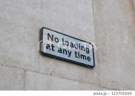 No loading at any time sign on a stone wall indicating parking and unloading restriction 123705884