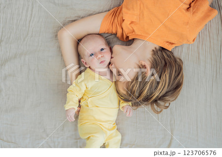 A young boy and his newborn brother lie together on a soft muslin blanket, sharing a tender sibling moment. A heartwarming scene of brotherly love, bonding, and the beginning of a lifelong connection 123706576