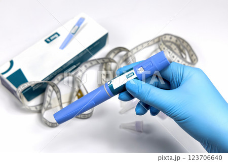 Hands in surgical gloves holding Ozempic Insulin injection pen for diabetics. 123706640
