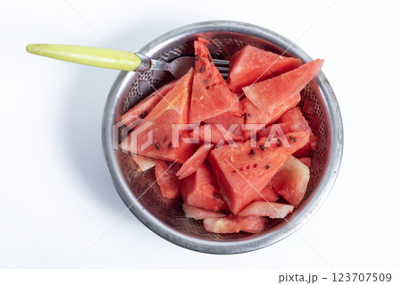 Freshly cut watermelon slices in a metal bowl with a fork on a white background, Top view 123707509