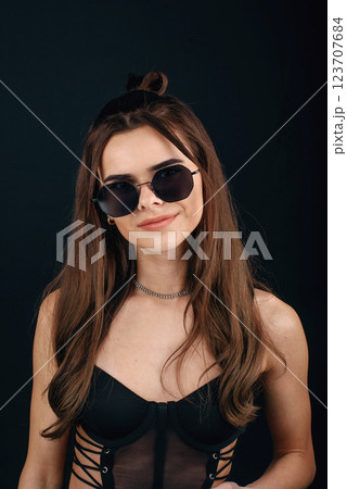 Young beautiful glamour girl posing in semi-transparent black dress and sunglasses on black background Young beautiful glamour girl posing in semi-transparent black dress and sunglasses on black background 123707684