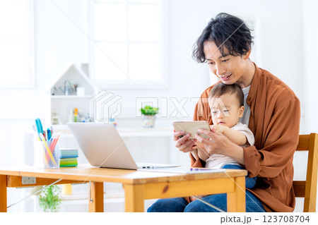 赤ちゃんの面倒を見ながら家で仕事をする男性 123708704