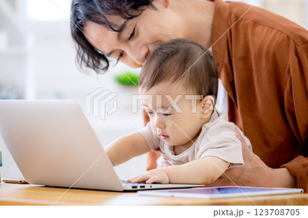 赤ちゃんの面倒を見ながら家で仕事をする男性 123708705
