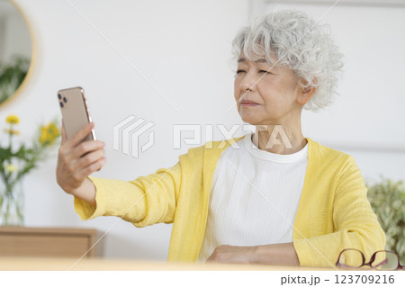目を細めてスマホの画面を見るシニア女性 目を細めてスマホの画面を見るシニア女性 123709216