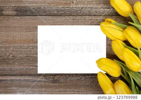 White card and yellow tulips on wooden rustic background. 123709998