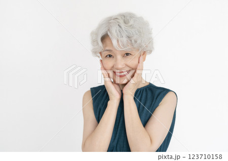 カメラ目線で笑顔の頬に手をあてたグレイヘアのシニア女性 123710158
