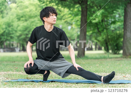 公園で運動前の準備運動・ウォーミングアップで屈伸するスポーツウェアの男性 公園で運動前の準備運動・ウォーミングアップで屈伸するスポーツウェアの男性 123710276