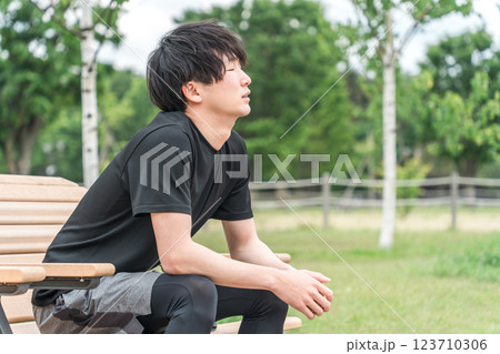 運動中に公園のベンチで休憩するアジア人男性（深呼吸・筋肉痛・オーバートレーニング症候群） 123710306