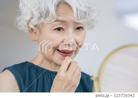 鏡に向かってメイクをするシニア女性 123710342
