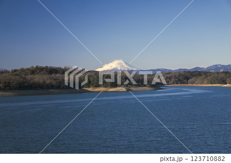 青空の冬の狭山湖堰堤から見る湖面と強風下の富士山 123710882