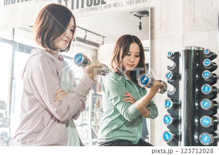 スポーツジムでワークアウト・運動筋トレ・ダイエット・トレーニングをする女性とトレーナー 123712028