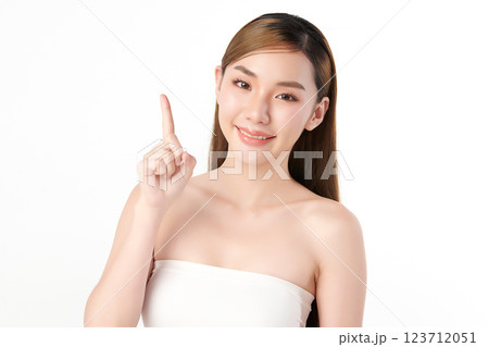A beautiful Asian woman with clear, radiant skin is raising one finger against a white background. Skincare, beauty, and spa. A beautiful Asian woman with clear, radiant skin is raising one finger against a white background. Skincare, beauty, and spa. 123712051