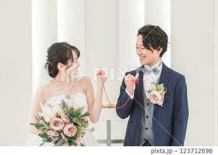 結婚式場で赤い糸で結ばれる新郎新婦（ブライダル・ウェディング） 123712696