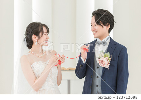 結婚式場で赤い糸で結ばれる新郎新婦（ブライダル・ウェディング） 123712698