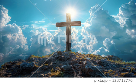 Illuminated wooden cross on grassy hilltop under bright blue sky with clouds. Symbol of faith, spirituality, and hope. 123712776