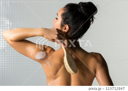 Woman applying body scrub while taking a shower in a modern bathroom 123712847