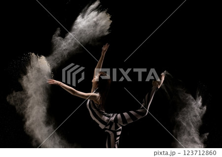 Dancer creating artistic patterns in flour with graceful movements Dancer creating artistic patterns in flour with graceful movements 123712860