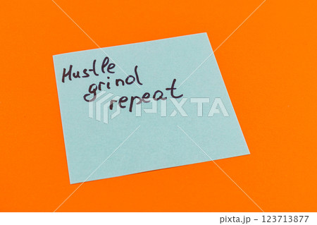 Hustle grind repeat written on a sticky note on vibrant orange background Hustle grind repeat written on a sticky note on vibrant orange background 123713877