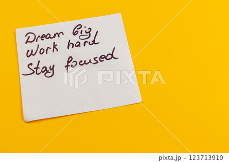Motivational note on yellow background encouraging dedication and focus 123713910