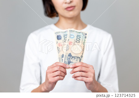 千円札を持って悩むミドル女性 千円札を持って悩むミドル女性 123714325