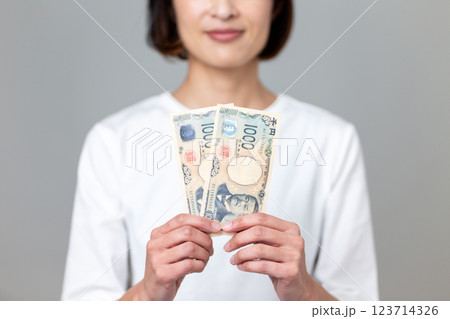 千円札を持って微笑むミドル女性 123714326
