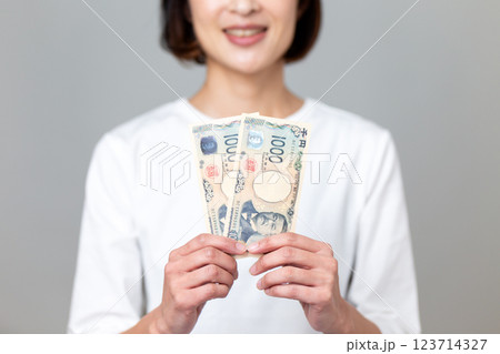 千円札を持って微笑むミドル女性 123714327