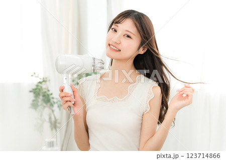 ヘアドライヤーでヘアブロー・髪の毛を乾かす女性（ヘアケア） 123714866