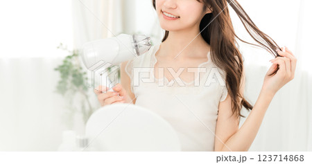 ヘアドライヤーでヘアブロー・髪の毛を乾かす女性（ヘアケア） 123714868