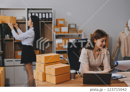 Startup SME small business entrepreneur of freelance Asian woman using a laptop with box Cheerful success Asian woman her hand lifts up online marketing packaging box and delivery SME idea concept 123715042