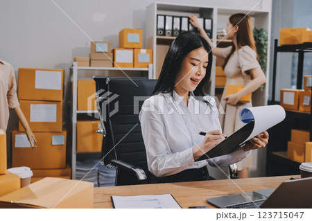 Asian SME business women use laptop computer checking customer order online shipping boxes at home. Starting Small business entrepreneur SME freelance. Online business, Work at home concept. Asian SME business women use laptop computer checking customer order online shipping boxes at home. Starting Small business entrepreneur SME freelance. Online business, Work at home concept. 123715047