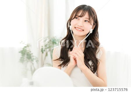 美顔ローラーを使ってマッサージするアジア人女性 美顔ローラーを使ってマッサージするアジア人女性 123715576