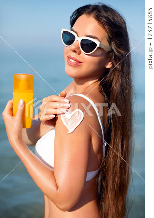 Woman Applying Sunscreen on Her Shoulder While Enjoying a Sunny Day at the Beach Woman Applying Sunscreen on Her Shoulder While Enjoying a Sunny Day at the Beach 123715885