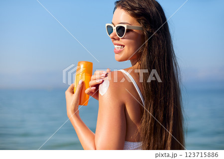 Enjoying Summer at the Beach While Applying Sunscreen for Skin Protection and Care Enjoying Summer at the Beach While Applying Sunscreen for Skin Protection and Care 123715886