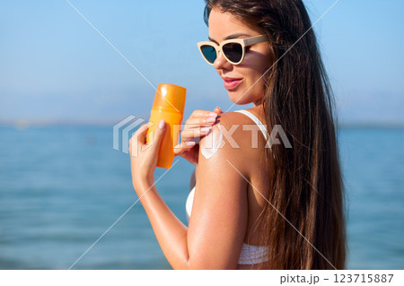 Enjoying Summer at the Beach While Applying Sunscreen for Sun Protection and Skincare Enjoying Summer at the Beach While Applying Sunscreen for Sun Protection and Skincare 123715887