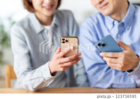 家でスマホを楽しそうに見るミドル夫婦 123716595