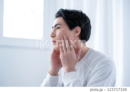 鏡で肌を確認する男性 123717189