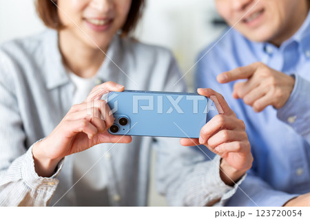 家でスマホを楽しそうに見るミドル夫婦 123720054