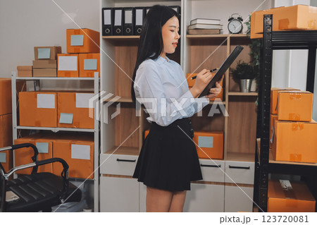 Startup SME small business entrepreneur of freelance Asian woman using a laptop with box Cheerful success Asian woman her hand lifts up online marketing packaging box and delivery SME idea concept 123720081