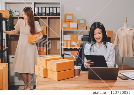 Startup SME small business entrepreneur of freelance Asian woman using a laptop with box Cheerful success Asian woman her hand lifts up online marketing packaging box and delivery SME idea concept 123720083