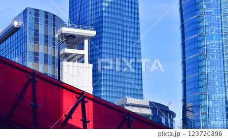 Glass building with transparent facade of the building and blue sky. Structural glass wall reflecting blue sky. Abstract modern architecture fragment. Contemporary architectural background. 123720896