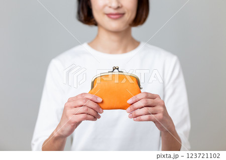 オレンジ色のがま口財布を持って微笑むミドル女性 オレンジ色のがま口財布を持って微笑むミドル女性 123721102