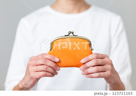 オレンジ色のがま口財布を持つミドル女性 123721103