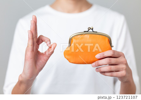 オレンジ色のがま口財布を持って丸サインをするミドル女性 123721107